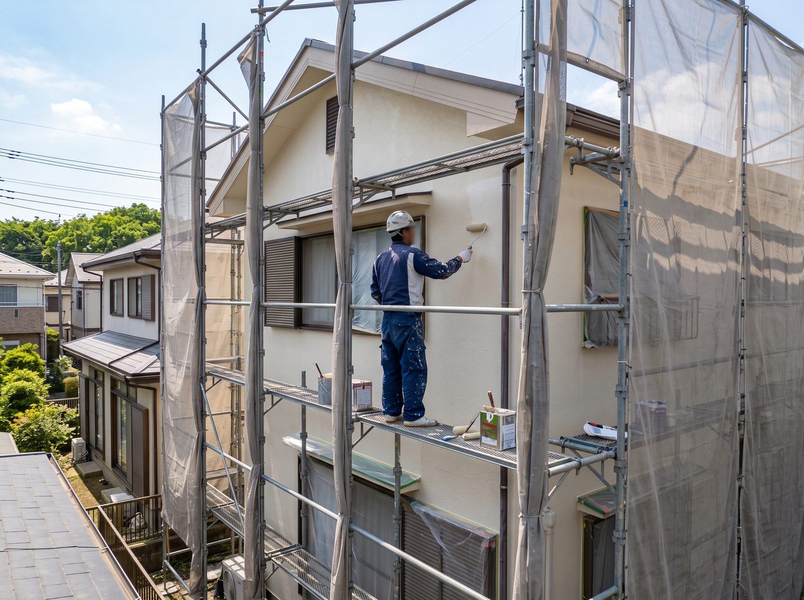 足場の上で外壁を塗装する職人